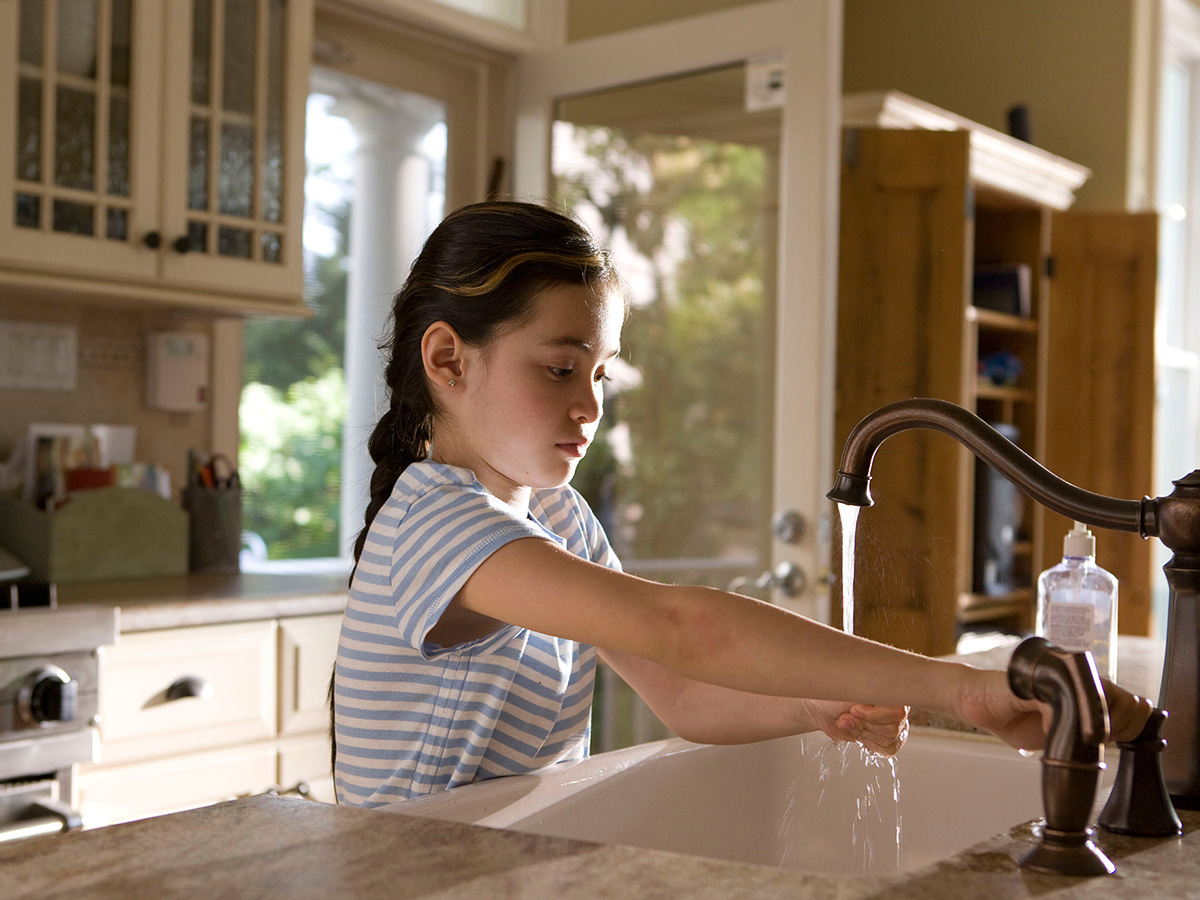 Young girl washing her hands in the kitchen