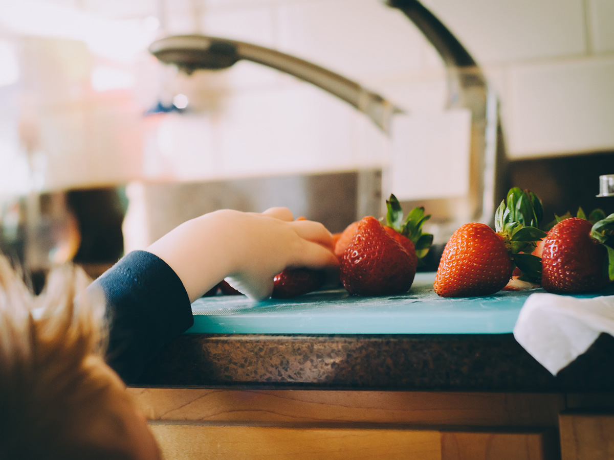 Young boy reaching for a recently washed strawberry