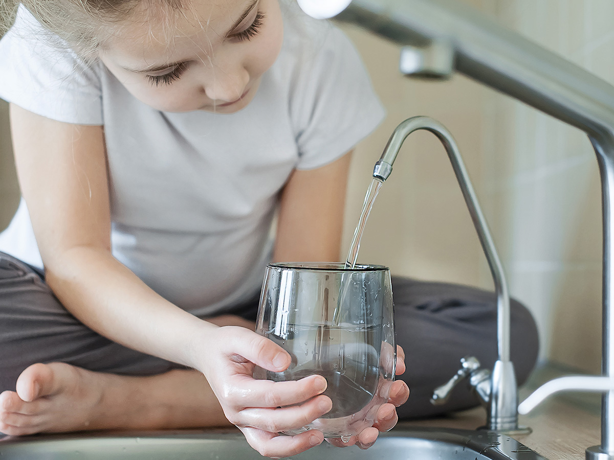 Little girl getting water to drink from a reverse osmosis filter tap